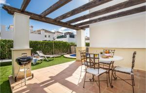 un patio con tavolo, sedie e griglia di 2 Bedroom Lovely Home In Roldan a Roldán