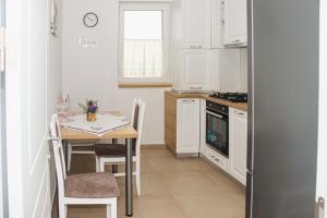 a kitchen with white cabinets and a table with chairs at Apartament Rubin in Sibiu