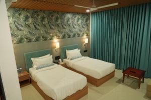 BarvālaSKD RESORT AND CLUB的配有绿窗帘的酒店客房的两张床