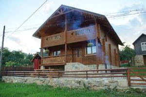 una grande cabina in legno con una recinzione di fronte ad essa di Eco Sadyba Familia a Jaremče