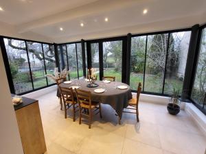 a dining room with a table and chairs and large windows at L'expérience Chartraine in Chartres