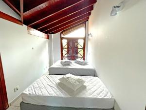 two beds in a room with a window at Canto do mar Maresias in Maresias