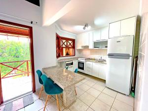 a kitchen with a white refrigerator and a table and chairs at Canto do mar Maresias in Maresias