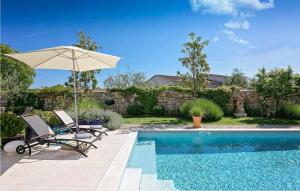 a patio with two chairs and an umbrella next to a pool at Villa Maxima Agri in Poreč