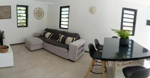 a living room with a couch and a table at Bungalow au Coeur du Vert RO 4 in Sainte-Anne +5 photos