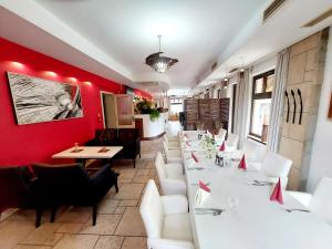 a restaurant with white tables and chairs and red walls at Hotel Slamený Dom & SPA in Košice