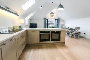 a large kitchen with white counter tops and wooden floors at Seashells Bracklesham Bay in Chichester +29 photos