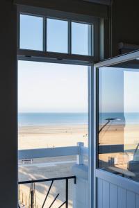 a view of the beach from the window of a beach house at Unieke villa Catherine met frontaal zeezicht, parking sauna en strandcabine in De Panne