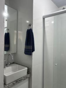 a white bathroom with a sink and a mirror at Flat 300m da Praia e Roda Gigante 2 andar com jacuzzi privativa in Balneário Camboriú