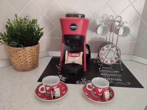 a red coffee maker and two cups on a counter at ross house in Fiumicino