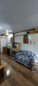 a bedroom with a bed in a room with a kitchen at Suíte o Pescador, praia do rosa in Garopaba