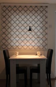 stół z krzesłami i lampka na ścianie w obiekcie Taf's Small House w Prisztinie