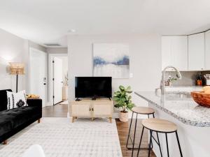a white living room with a black couch and a kitchen at Cozy 1-Bedroom Retreat, New Remodel, Fast Wi-Fi in Columbus