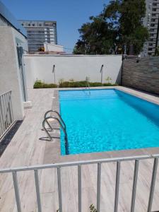 a large blue swimming pool with a fence around it at Departamento la Cisterna in Santiago