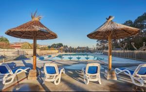 a group of chairs and umbrellas next to a pool at Résidence Domaine Iratzia Erromardie - Appartement T2 in Saint-Jean-de-Luz