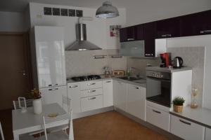 a kitchen with white cabinets and a table and a stove at ross house in Fiumicino