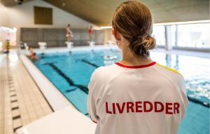 a woman standing in front of a swimming pool at Hytte 7 in Thyborøn