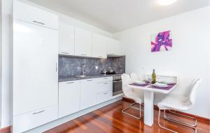 a kitchen with white cabinets and a table and chairs at Lovely Apartment In Malinska With Wifi in Malinska