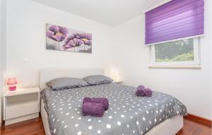 a bedroom with a bed with purple pillows and a window at Lovely Apartment In Malinska With Wifi in Malinska