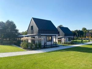 a house with a black roof and green grass at Domy pod Borczyną in Zwierzyniec