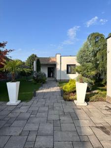 una casa con dos grandes jarrones blancos en el patio en Villa Kulacs, en Veľký Meder