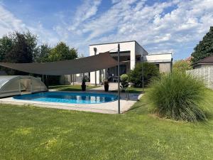 a swimming pool in a yard with a retractable umbrella at Villa Kulacs in Veľký Meder