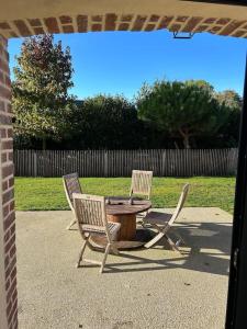two chairs and a table in a yard with a fence at Gites les Amourettes in Saint-Aubin-sur-Scie