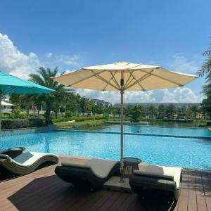 a pool with chairs and an umbrella next to a swimming pool at Hoàng Gia villa Novaworld in Bình Sum