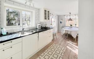 a white kitchen with a sink and a table at Amazing Home In Köpmannebro With Wifi in Åsensbruk +11 photos