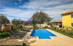 a swimming pool with lounge chairs and umbrellas next to a house at Villa Ive in Orbanići +45 photos