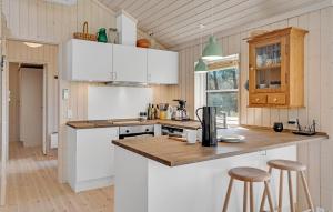 a kitchen with white cabinets and a counter with stools at Stunning Home In Sjællands Odde in Yderby