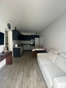 a living room with a white couch and a kitchen at Charmante maison avec terrasse in Auterive