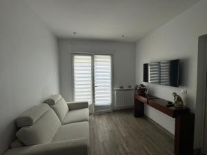 a living room with a white couch and a television at Charmante maison avec terrasse in Auterive +4 photos