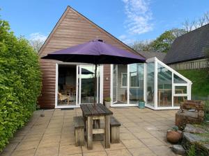 a patio with an umbrella and a wooden table at Coombe Corner Cornwall in Bude