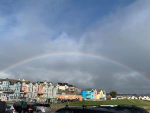 a rainbow in the sky over a parking lot with cars at Coombe Corner Cornwall in Bude +33 photos
