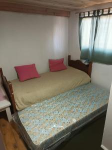 a small bedroom with two beds with red pillows at El Campito in Necochea