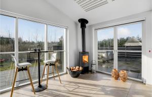 a living room with a fireplace and large windows at Awesome Home In Blåvand With Sauna in Blåvand