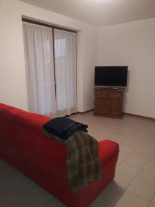 Il comprend un salon doté d'un canapé rouge et d'une télévision à écran plat. dans l'établissement La casa dei nonni, à Villafranca di Verona