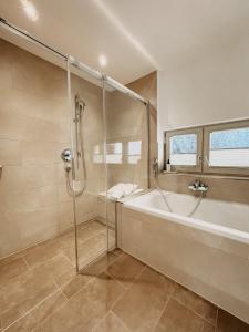 a bathroom with a shower and a bath tub at Hotel Hofwirt Neubeuern in Neubeuern +112 photos