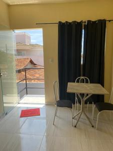 a table and chairs in a room with a window at Flats com ar condicionado, garagem e internet in Pirapora