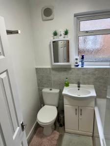 a bathroom with a toilet and a sink and a window at Shouth Harrow in Harrow on the Hill +2 photos