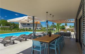 une terrasse avec une table et des chaises en bois ainsi qu'une piscine dans l'établissement Villa Povetica, à Poreč