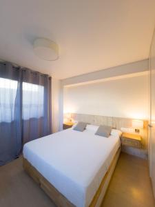 Un dormitorio con una gran cama blanca y una ventana. en Apartamento en la playa, en Castelldefels