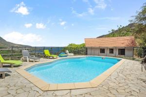 a swimming pool with chairs and a house at Chalet Flambwayan, quiet, peaceful and well located in Les Anses-dʼArlets