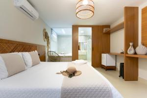 a bedroom with a white bed with a hat on it at Pousada Timoneiro in Ponta da Fruta