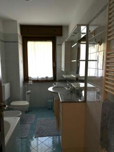 un bagno con due lavandini, un water e una finestra di DepaHOME a Saint Vincent Altre 22 foto