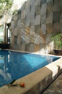 a swimming pool with a geometric wall next to it at Hotel Casa Palomino in Mérida