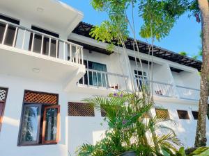 a white building with trees in front of it at Lake Duwa Hotel in Ambalangoda