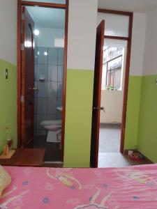 a bedroom with a bed and a bathroom with a toilet at Kusi Wasi in Moyobamba