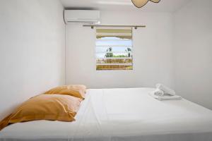 a white room with a bed with a window at Appartement Rosalia, cosy & central in Fort-de-France